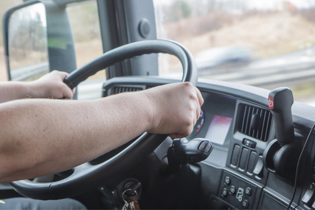 truck driver holding steering wheel with Commercial Auto Insurance